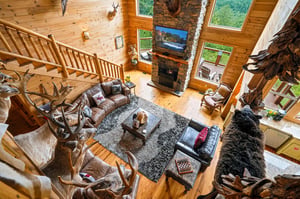 Your spacious mountain retreat features soaring cathedral ceilings, a stunning stone fireplace, and oversized windows framing lush forest views. Cozy leather seating invites you to relax in rustic ele