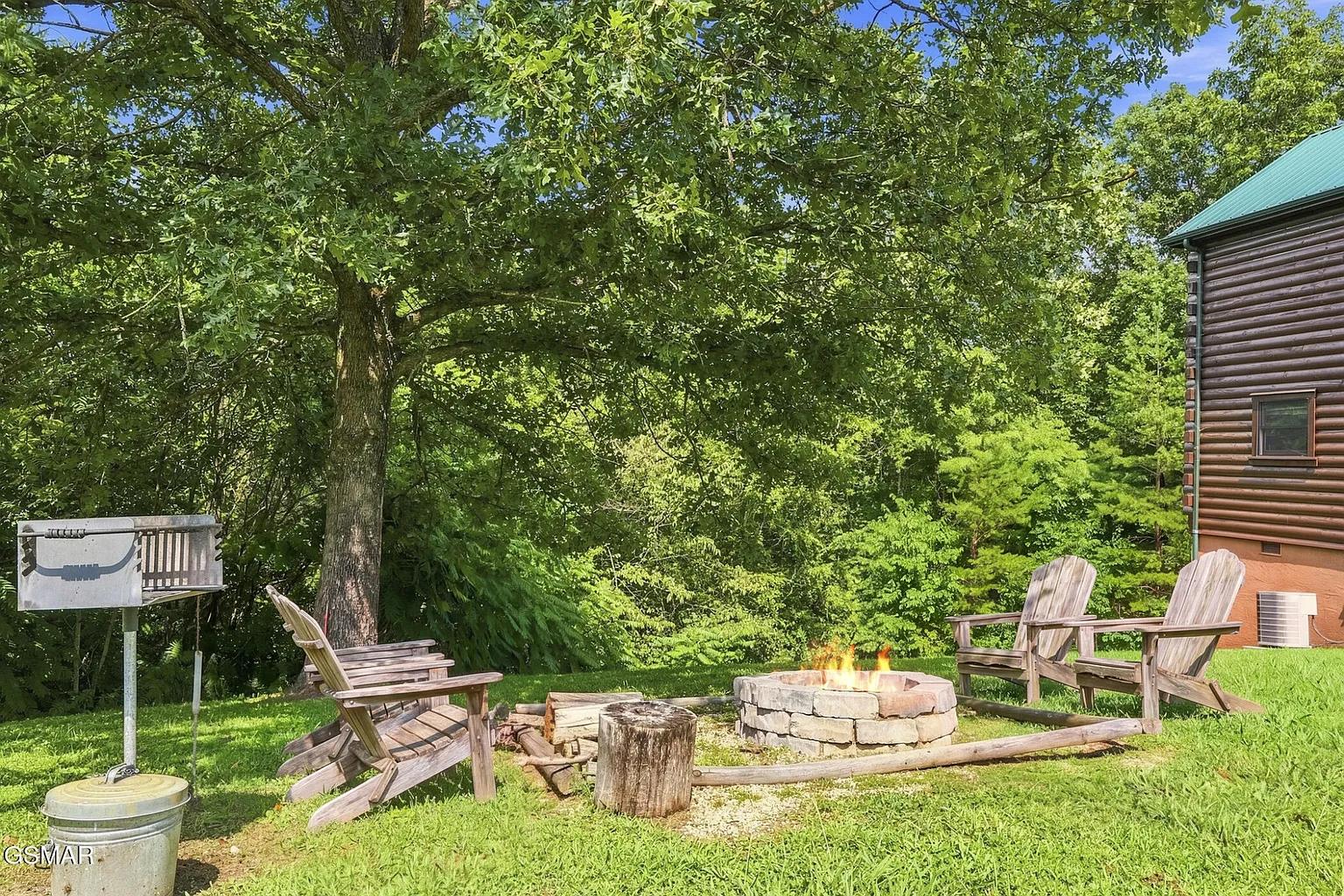 A stone firepit surrounded by Adirondack chairs awaits your evenings under the trees, where crackling flames and fresh air create the perfect gathering spot.