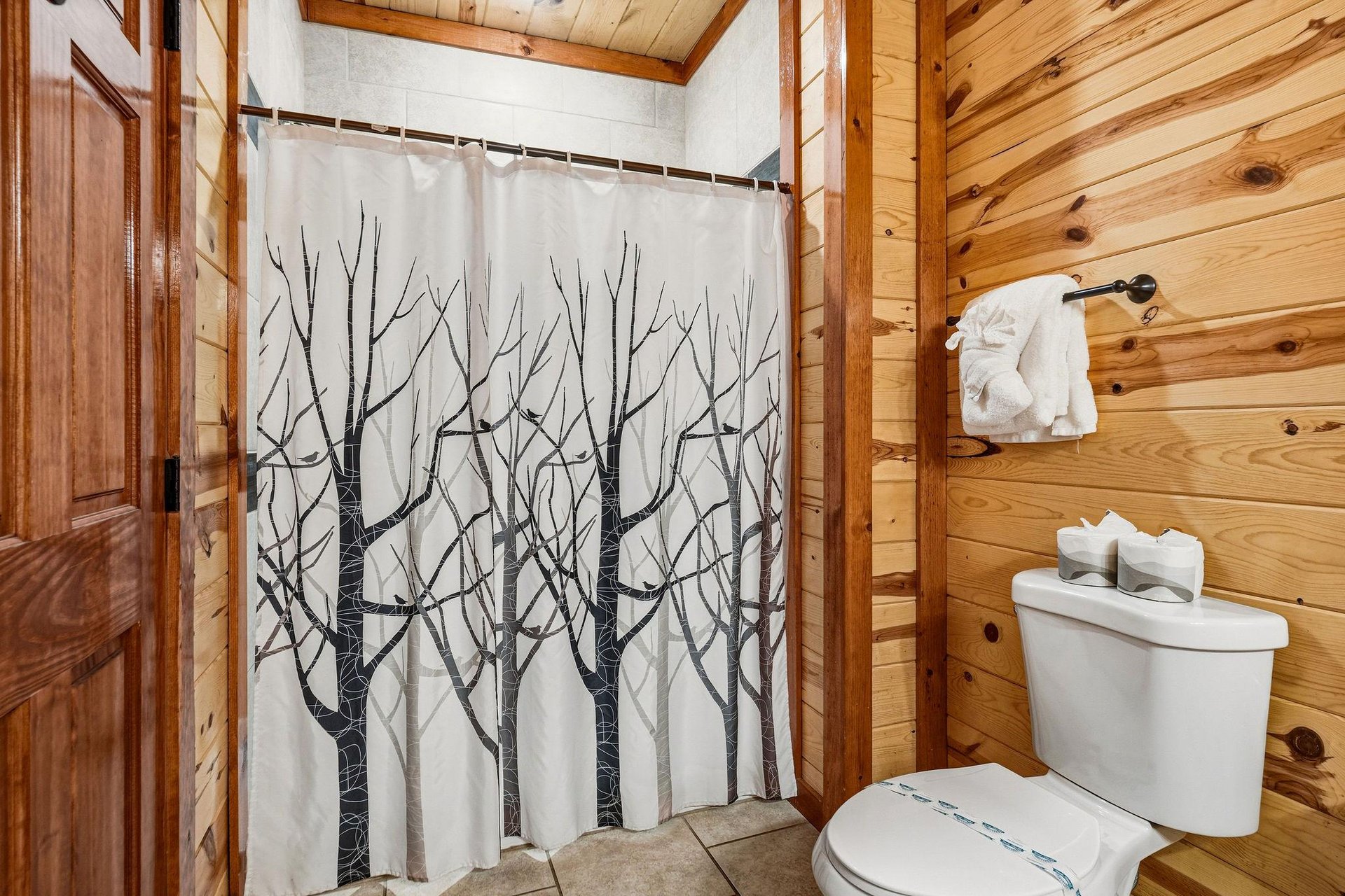 Refresh in your rustic bathroom with warm wood walls and a natureinspired shower curtain that brings the outdoors in.