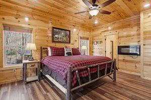 Drift off in this charming log cabin bedroom where rustic wood beams meet cozy buffalo plaid bedding for the perfect mountain retreat.