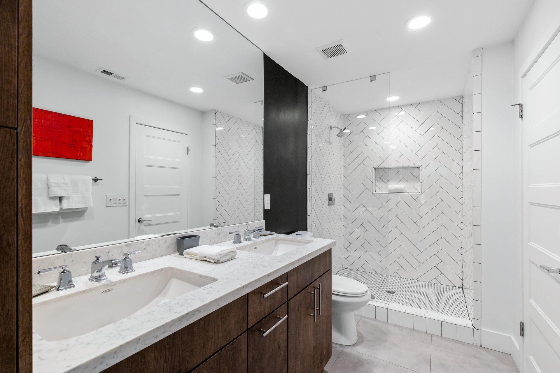 Features a walkin shower and dual vanity sink.