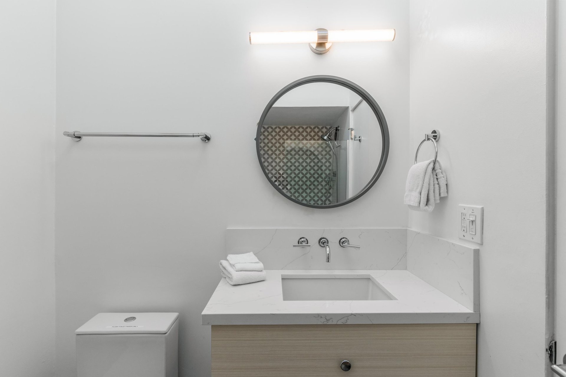 Fresh white towels await you in this bright, modern bathroom with stylish marble countertop and sleek fixtures.