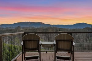 Sunset paints the sky in brilliant purples and gold as mountain silhouettes frame your private balcony retreat.
