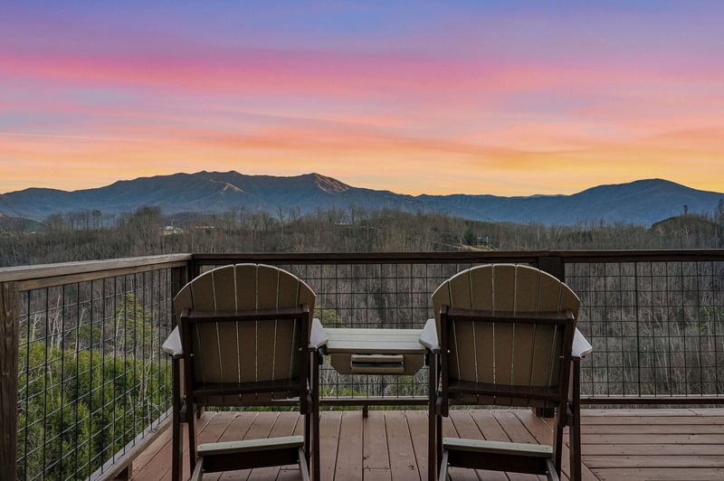 Sunset paints the sky in brilliant purples and gold as mountain silhouettes frame your private balcony retreat.