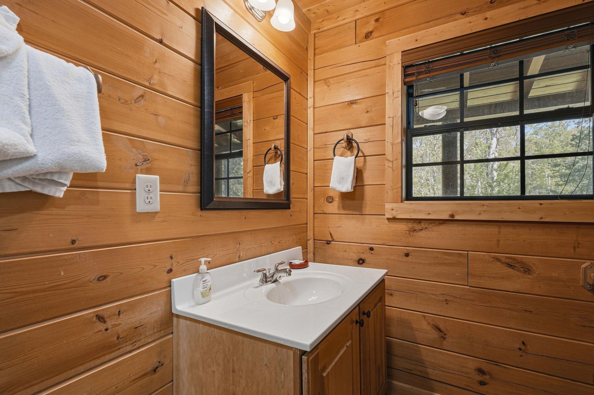 Refresh in your rustic wooden bathroom with warm cabin charm, complete with fluffy towels and natural light streaming through windows.