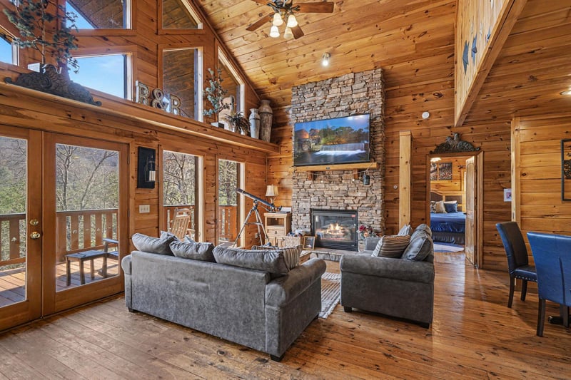 Sink into plush sofas by your crackling stone fireplace, where soaring wood ceilings and panoramic windows create your perfect mountain retreat sanctuary.