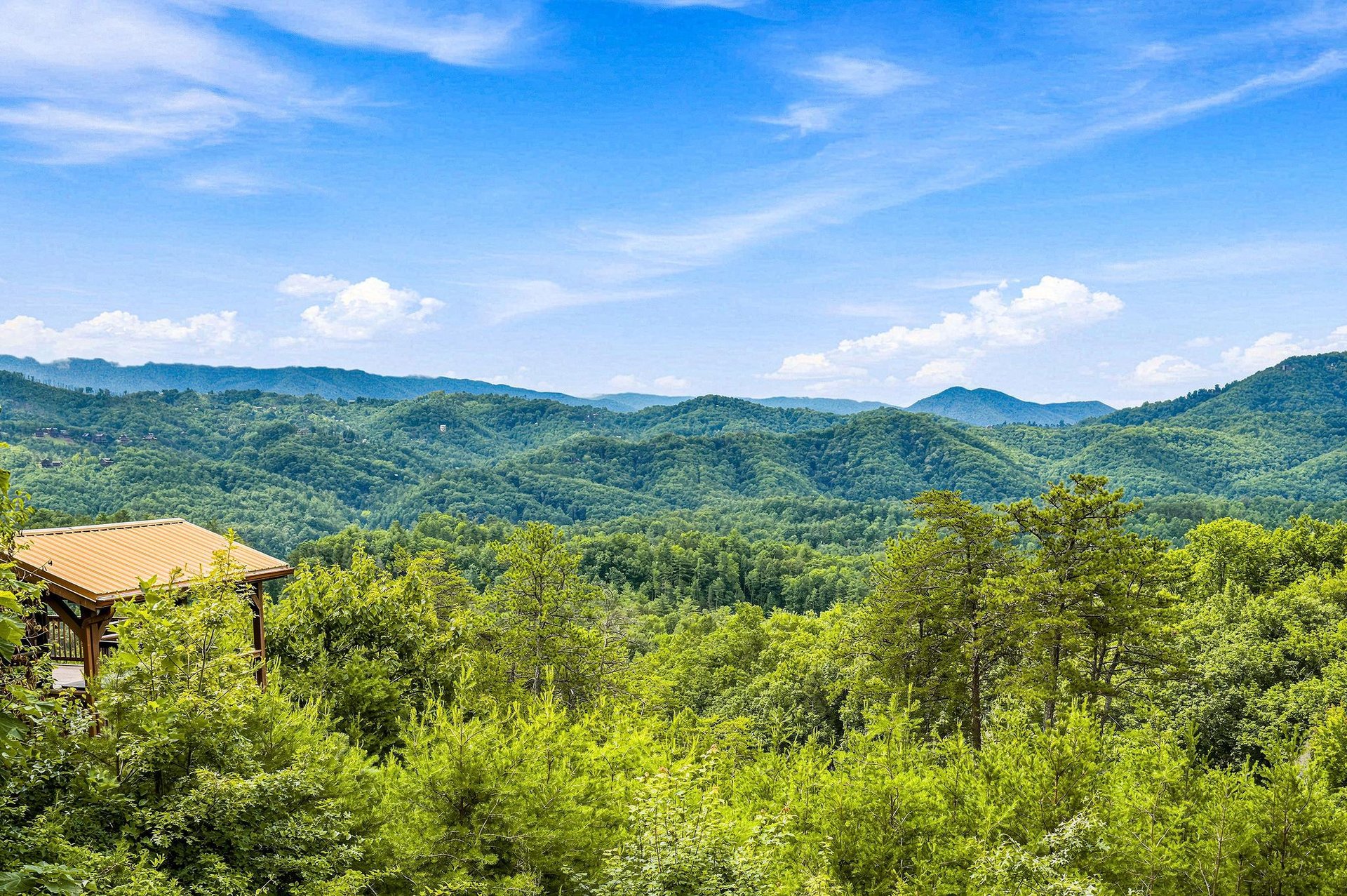 Panoramic mountain vistas stretch endlessly across lush forested peaks beneath a brilliant blue sky, offering a breathtaking natural backdrop to your stay.