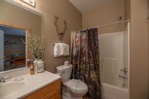 Bathroom with a tub and shower attached to bedroom and game room