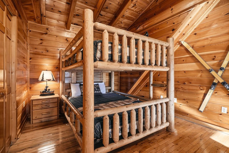 Rustic handcrafted log bunk beds bring warmth and mountain charm to this cozy bedroom. A peaceful retreat for restful nights beneath the natural wood ceiling.
