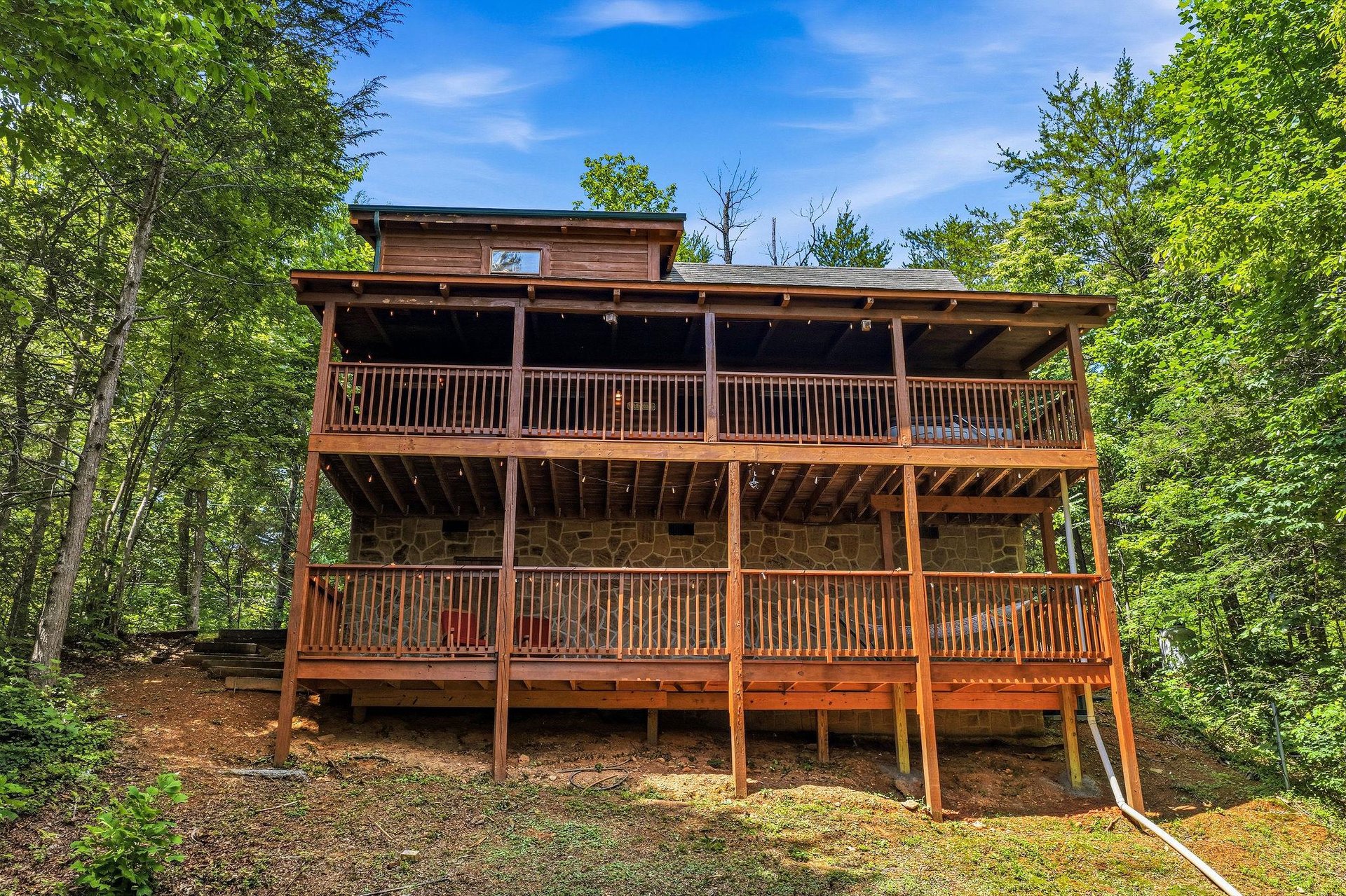 This striking wooden cabin is nestled within a lush, private forest setting, featuring spacious multilevel decks surrounded by towering trees and natural beauty—perfect for a peaceful mountain getawa