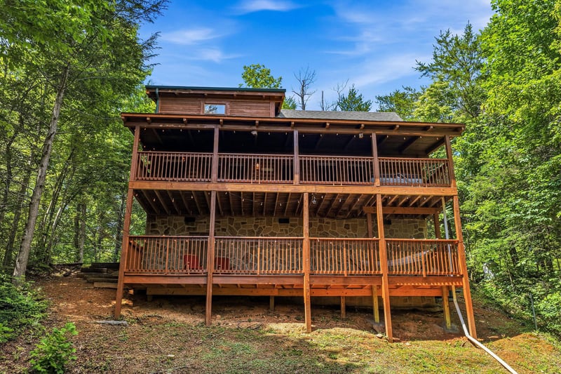 This striking wooden cabin is nestled within a lush, private forest setting, featuring spacious multilevel decks surrounded by towering trees and natural beauty—perfect for a peaceful mountain getawa