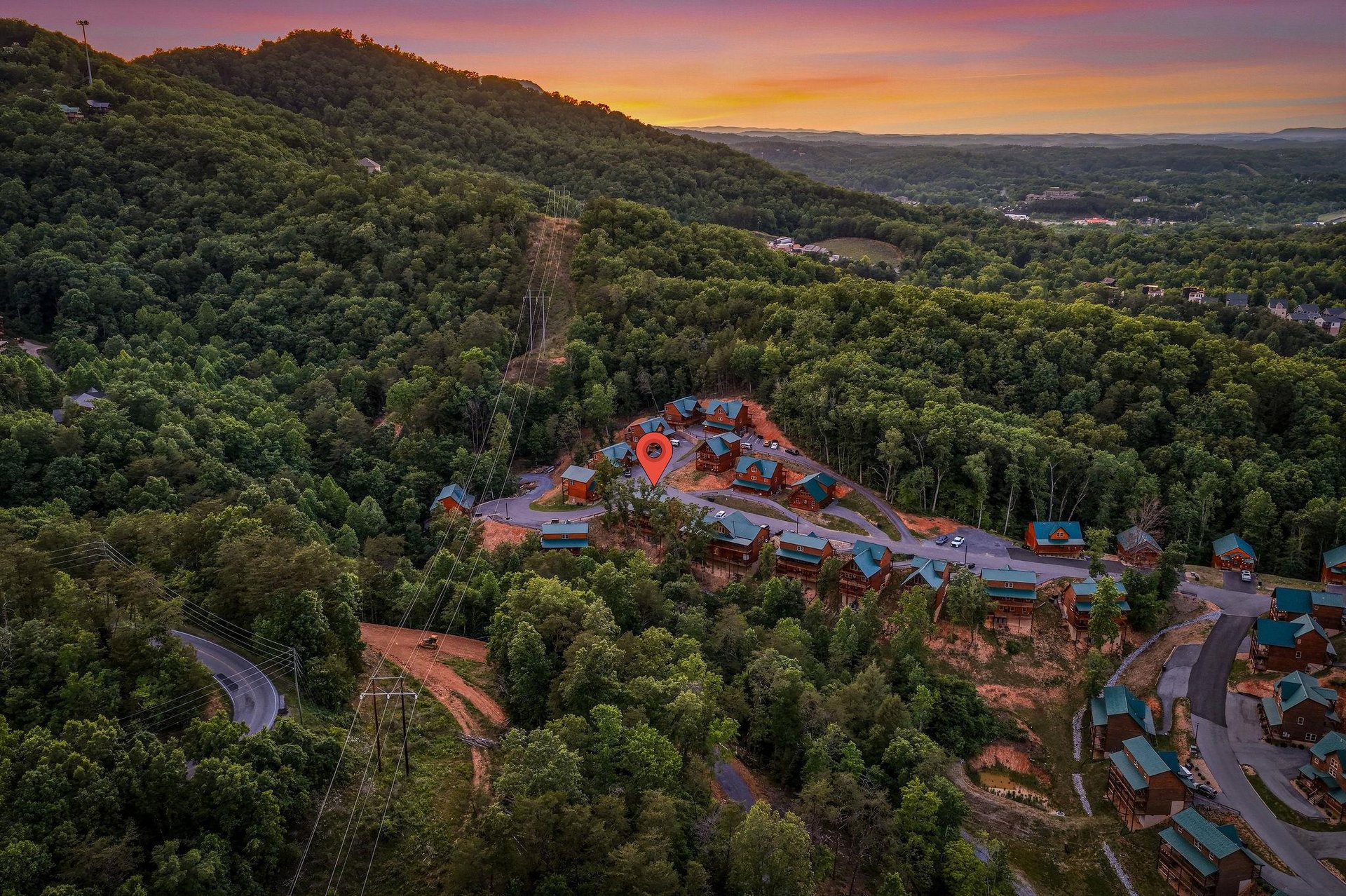 An aerial view captures the property nestled among lush hillsides at sunset, showcasing the peaceful mountain setting and natural landscape of the surrounding area.