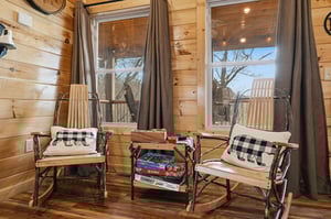 Cozy reading nook with handcrafted rocking chairs and nature views invites you to unwind with board games and peaceful moments.