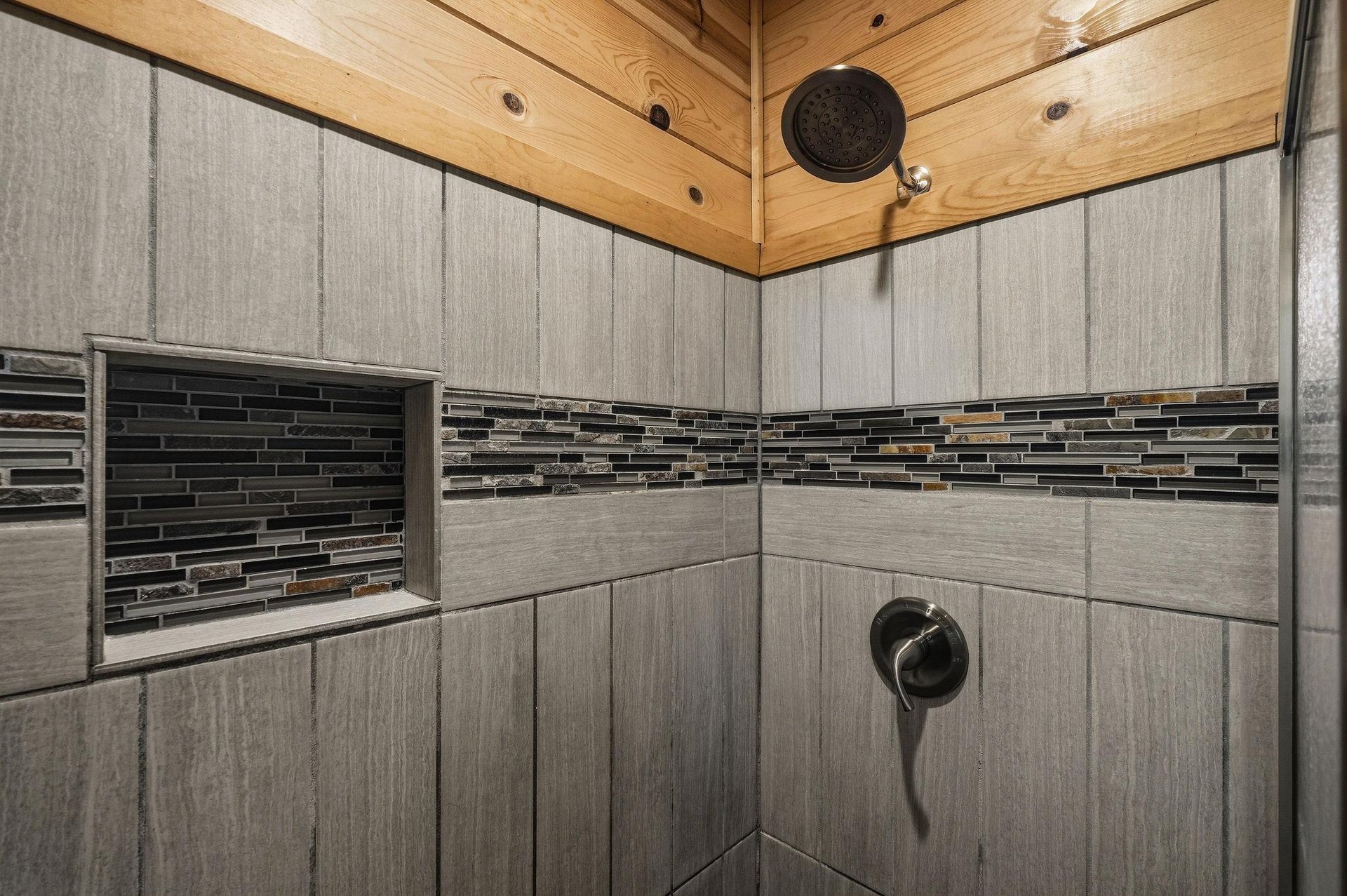 Rinse away the day in your beautifully tiled walkin shower with warm woodpaneled ceiling, thoughtful builtin niche, and modern rainfall showerhead.
