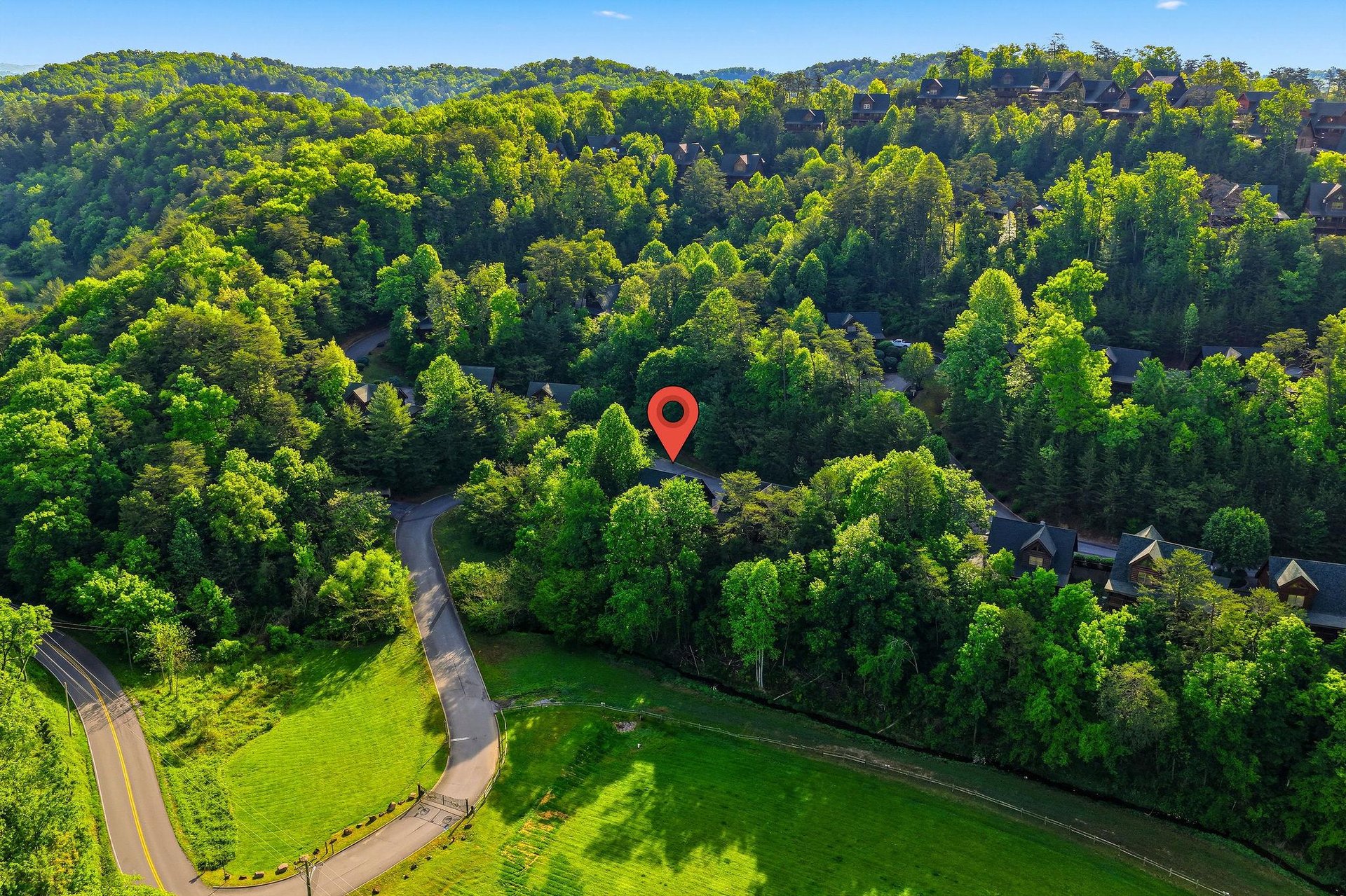Aerial view of property nestled among rolling hills and lush forest, offering secluded privacy in a scenic natural setting.