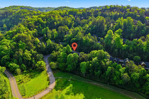 Aerial view of property nestled among rolling hills and lush forest, offering secluded privacy in a scenic natural setting.