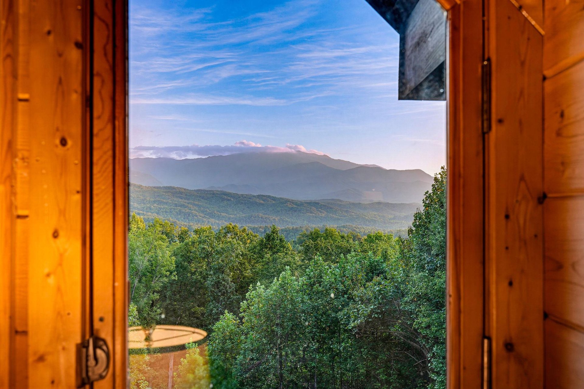 This mountain retreat frames breathtaking layered peaks and forest through open doors, offering a stunning natural landscape perfect for peaceful escapes.