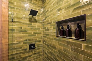 Step into this beautifully tiled shower with sleek green subway tiles, a modern rainfall showerhead, and luxury bath amenities waiting for you.