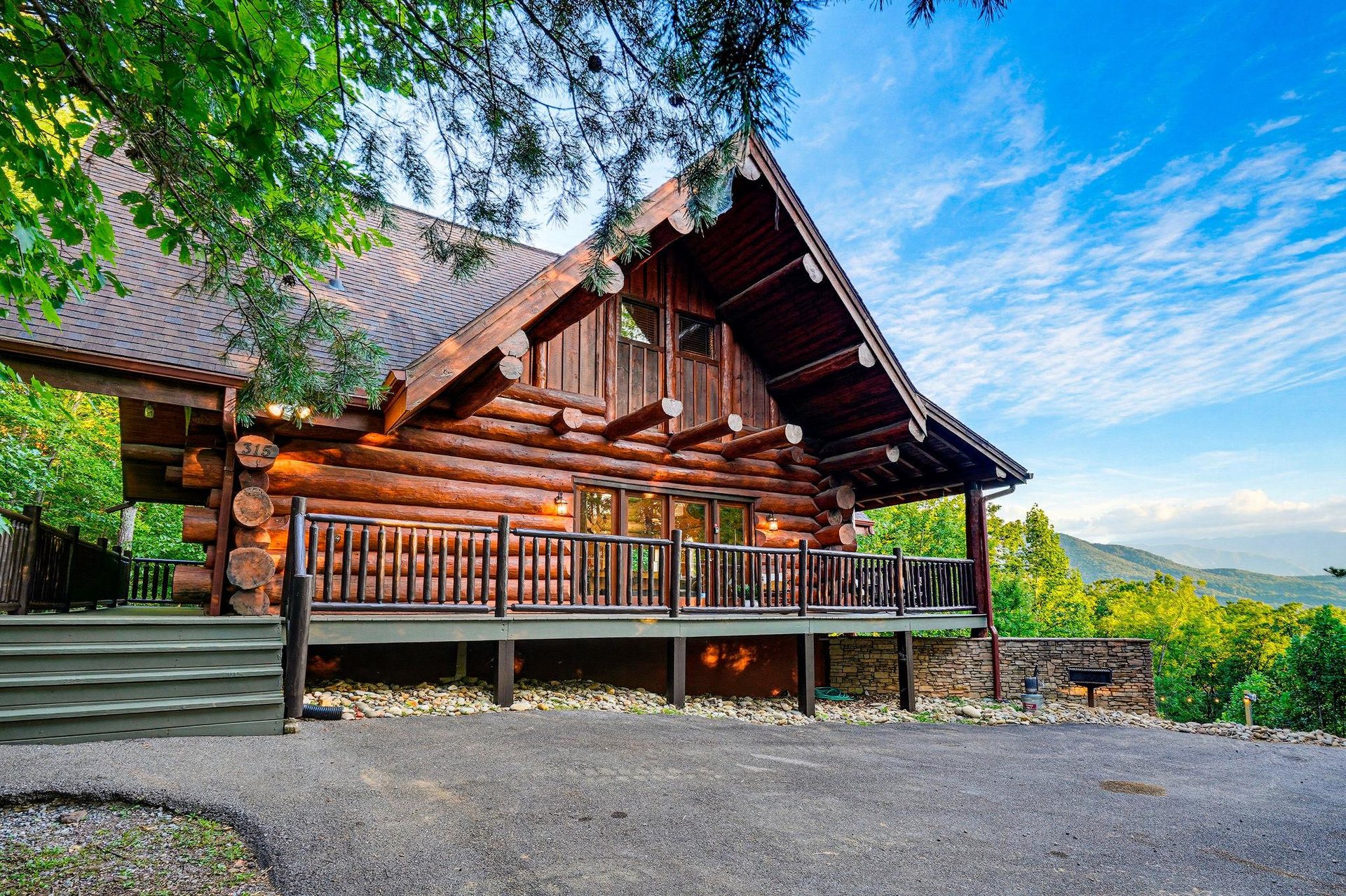 A handcrafted log cabin framed by lush greenery, showcasing rustic wood detailing and a welcoming deck that overlooks the surrounding mountains—the perfect mountain retreat.