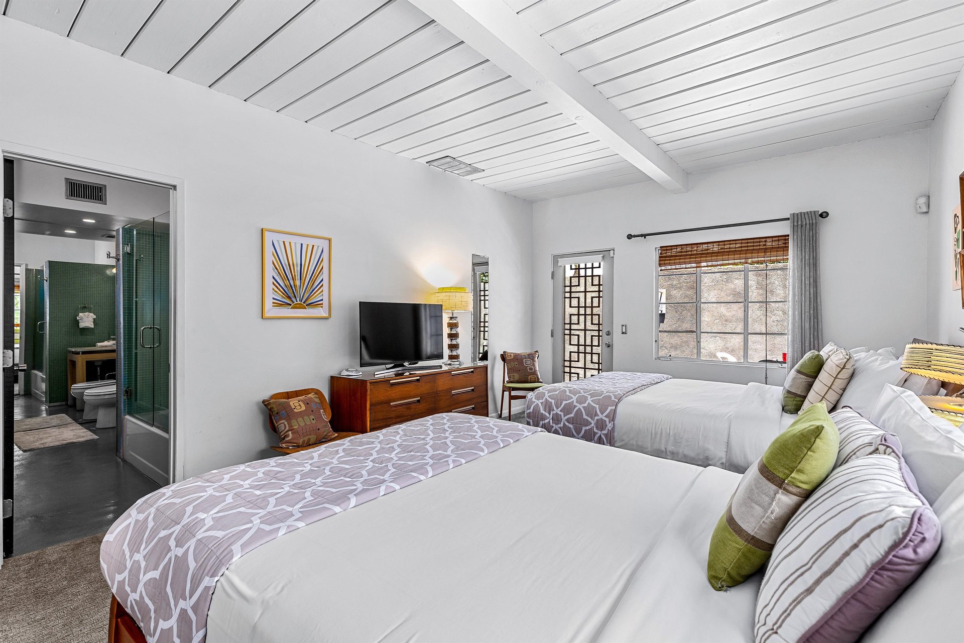 View of TV on dresser and private patio door from queen bed