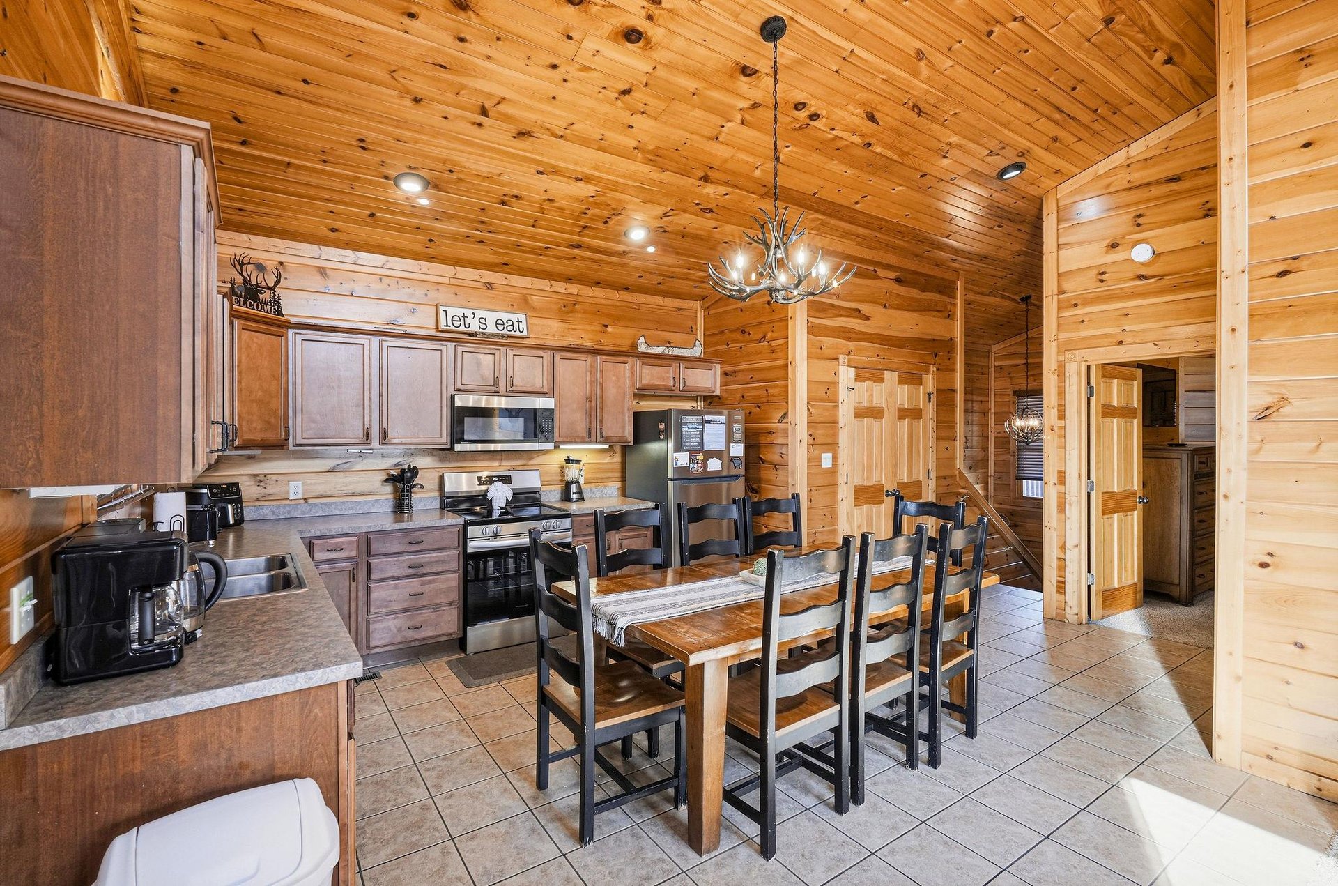 Gather around this rustic dining table where warm wood surrounds you and the antler chandelier sets the perfect cabin mood for memorable meals.