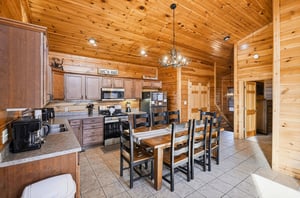 Gather around this rustic dining table where warm wood surrounds you and the antler chandelier sets the perfect cabin mood for memorable meals.