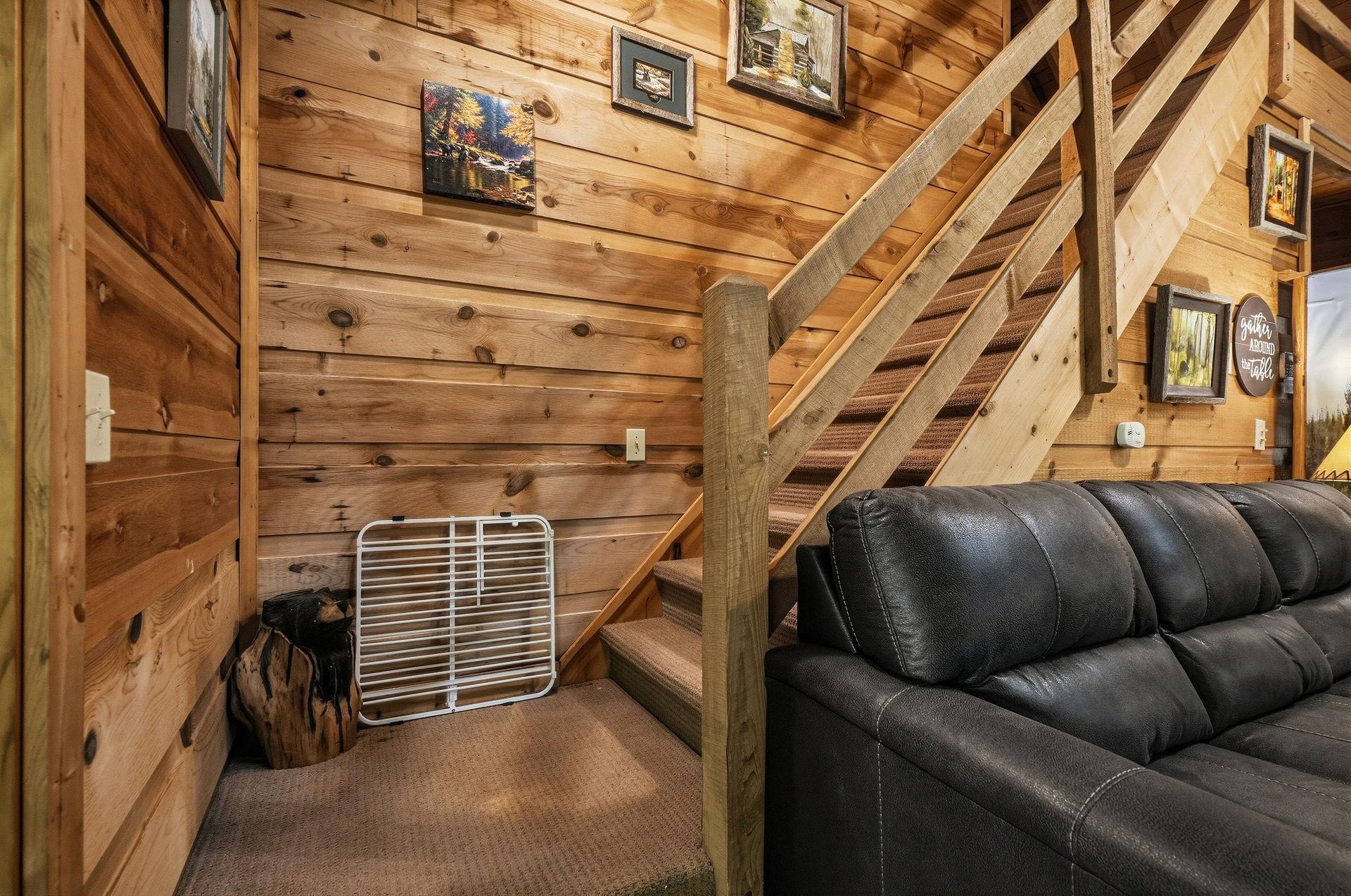 Sink into the plush leather sofa as you admire the rustic charm of knotty pine walls and handcrafted wooden stairs leading to your cozy loft retreat above.