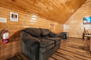 Sink into the plush sofa in this cozy woodpaneled retreat, where warm natural tones and vaulted ceilings create your perfect escape for relaxing evenings.
