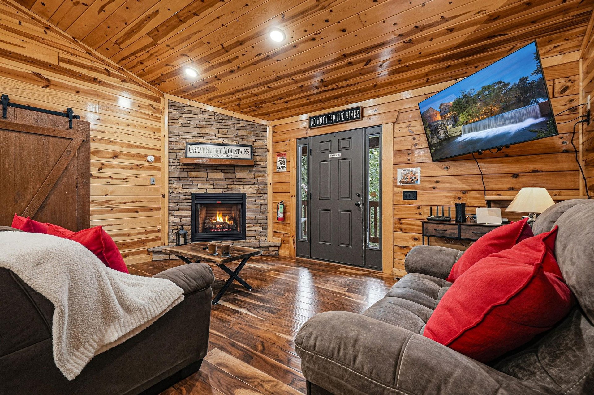 Cozy up in your cabin retreat with rich wood walls, a glowing fireplace, and plush seating perfect for unwinding after a day of mountain adventures.