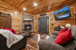 Cozy up in your cabin retreat with rich wood walls, a glowing fireplace, and plush seating perfect for unwinding after a day of mountain adventures.