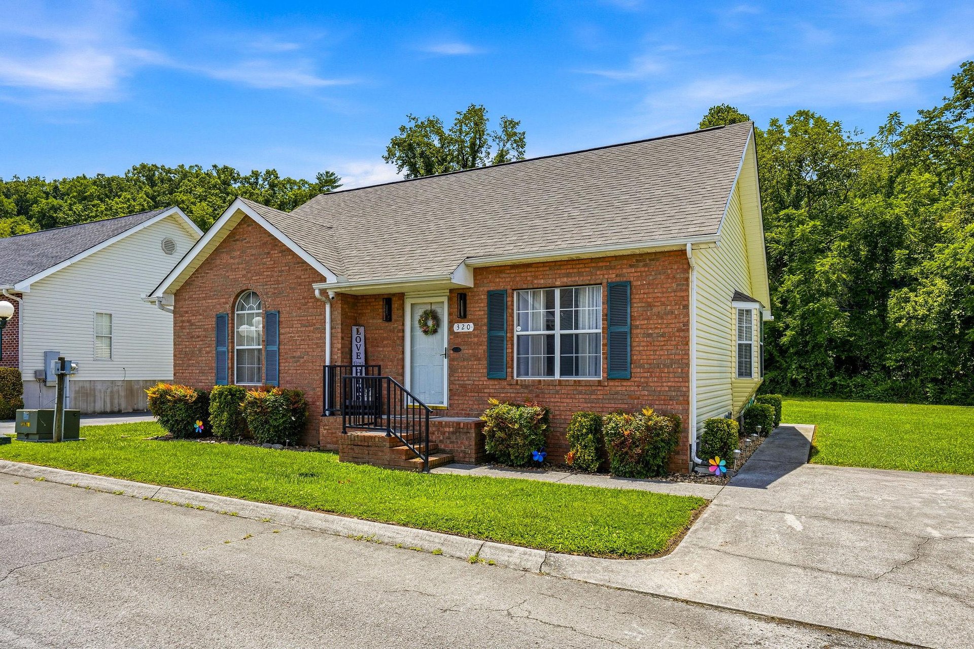 Charming brick property nestled in a quiet neighborhood surrounded by lush trees, offering a welcoming retreat for guests.