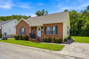 Charming brick property nestled in a quiet neighborhood surrounded by lush trees, offering a welcoming retreat for guests.