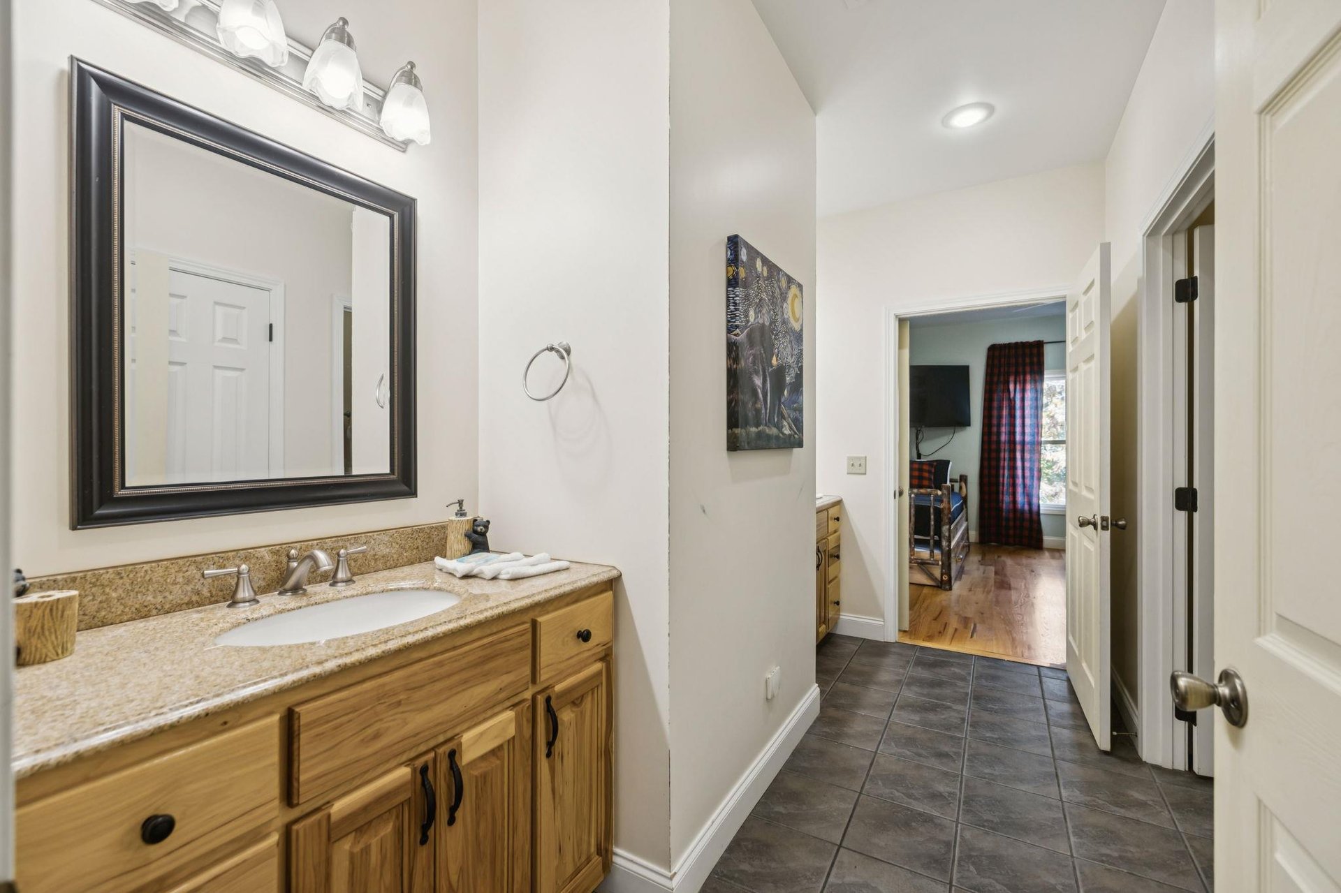 Your private bathroom features a granitetopped vanity with elegant lighting and a framed mirror, offering plenty of space to freshen up in comfort.