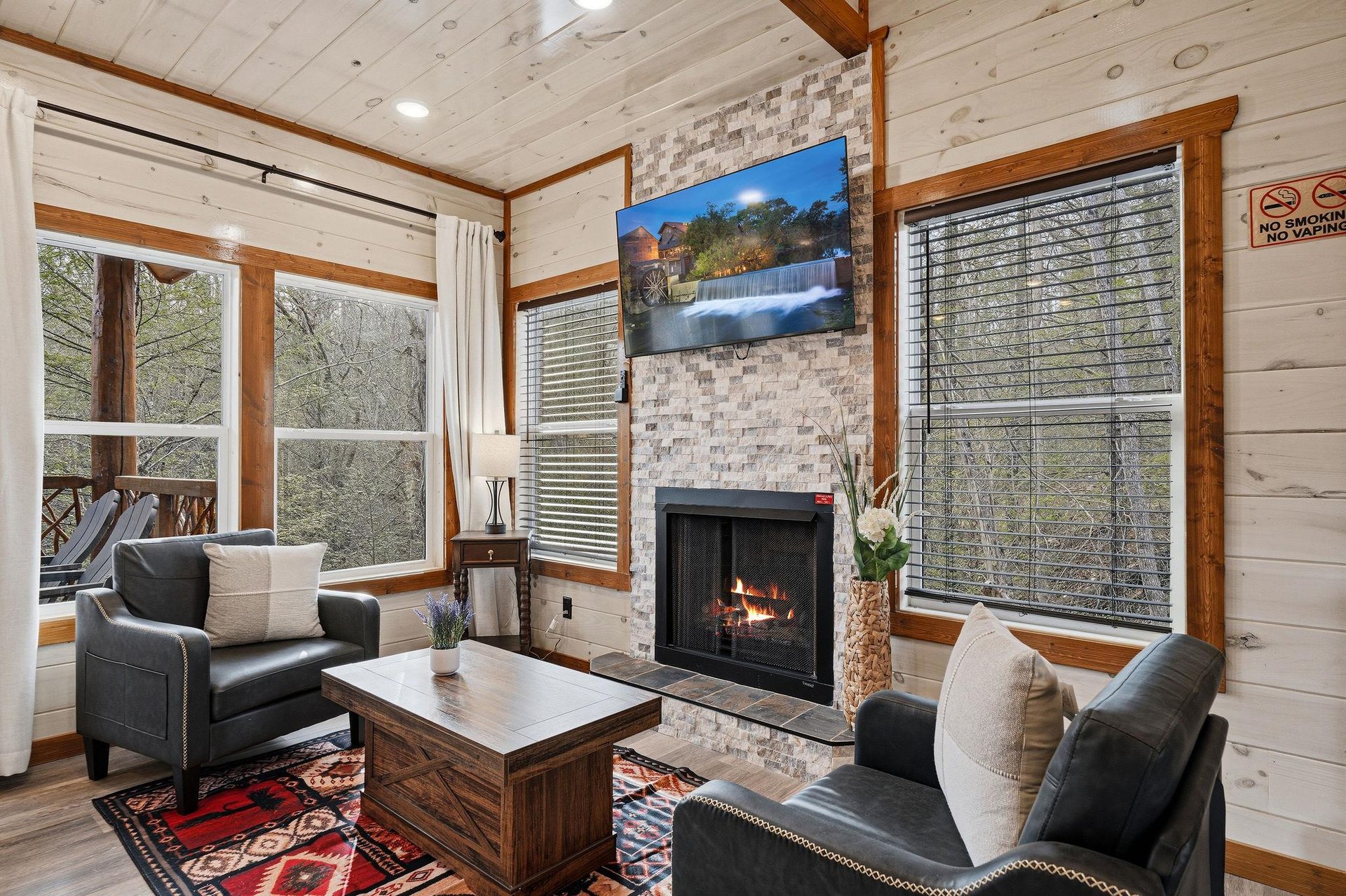 Cozy up by your crackling fireplace while enjoying forest views through floortoceiling windows in this warm, rustic living space.