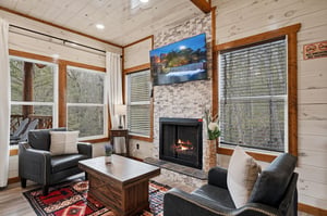 Cozy up by your crackling fireplace while enjoying forest views through floortoceiling windows in this warm, rustic living space.