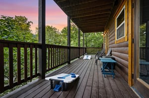 Unwind on your private deck with games ready for evening fun as sunset paints the sky in stunning hues above the treetops.