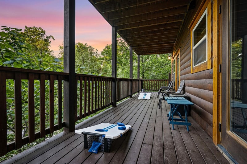 Unwind on your private deck with games ready for evening fun as sunset paints the sky in stunning hues above the treetops.