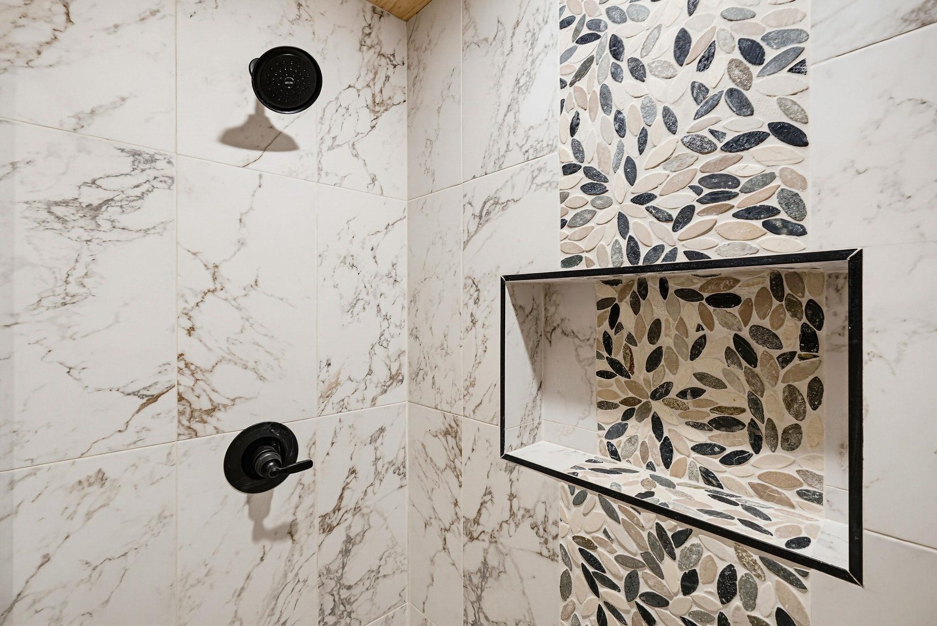 Elegant marble and mosaic tile create a spalike shower retreat, where each wash feels like a refreshing escape.