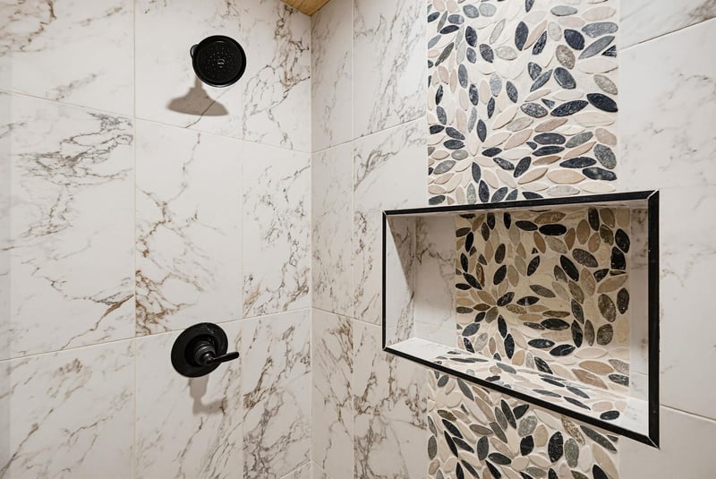 Elegant marble and mosaic tile create a spalike shower retreat, where each wash feels like a refreshing escape.