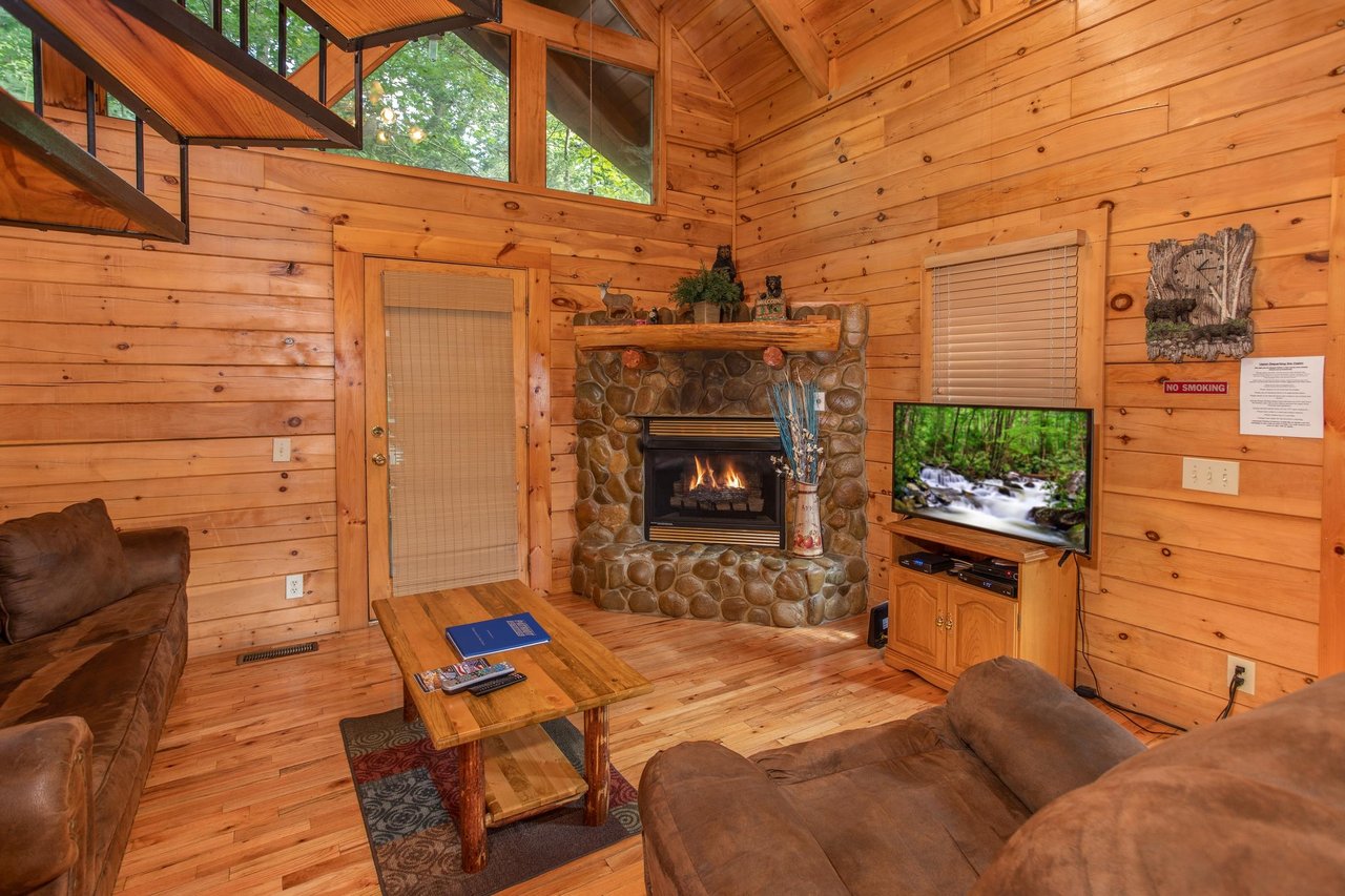 Living room with a fireplace, television, and vaulted ceiling at Dreams Do Come True, a 1bedroom cabin rental located in Pigeon Forge