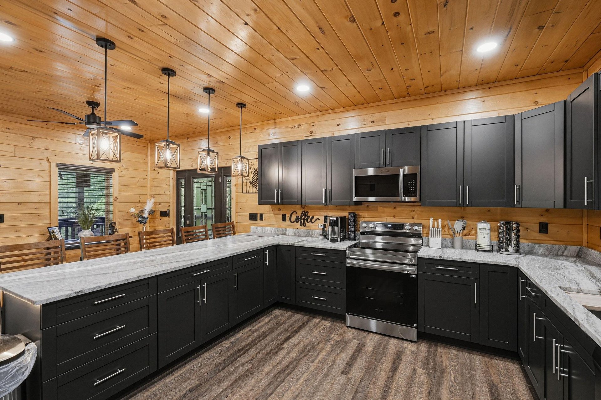 Your fully equipped kitchen awaits with sleek dark cabinetry, granite countertops, and rustic wood ceilings that create the perfect mountain retreat atmosphere.