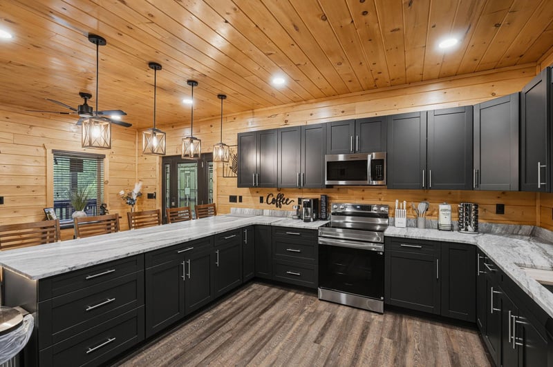 Your fully equipped kitchen awaits with sleek dark cabinetry, granite countertops, and rustic wood ceilings that create the perfect mountain retreat atmosphere.