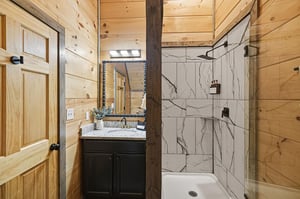 Unwind in your rusticchic bathroom featuring a stunning marble shower and rich wood accents for the perfect mountain retreat.