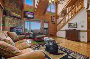 Sink into plush leather seating by your stone fireplace, where rustic wood beams frame mountain views through soaring windows.