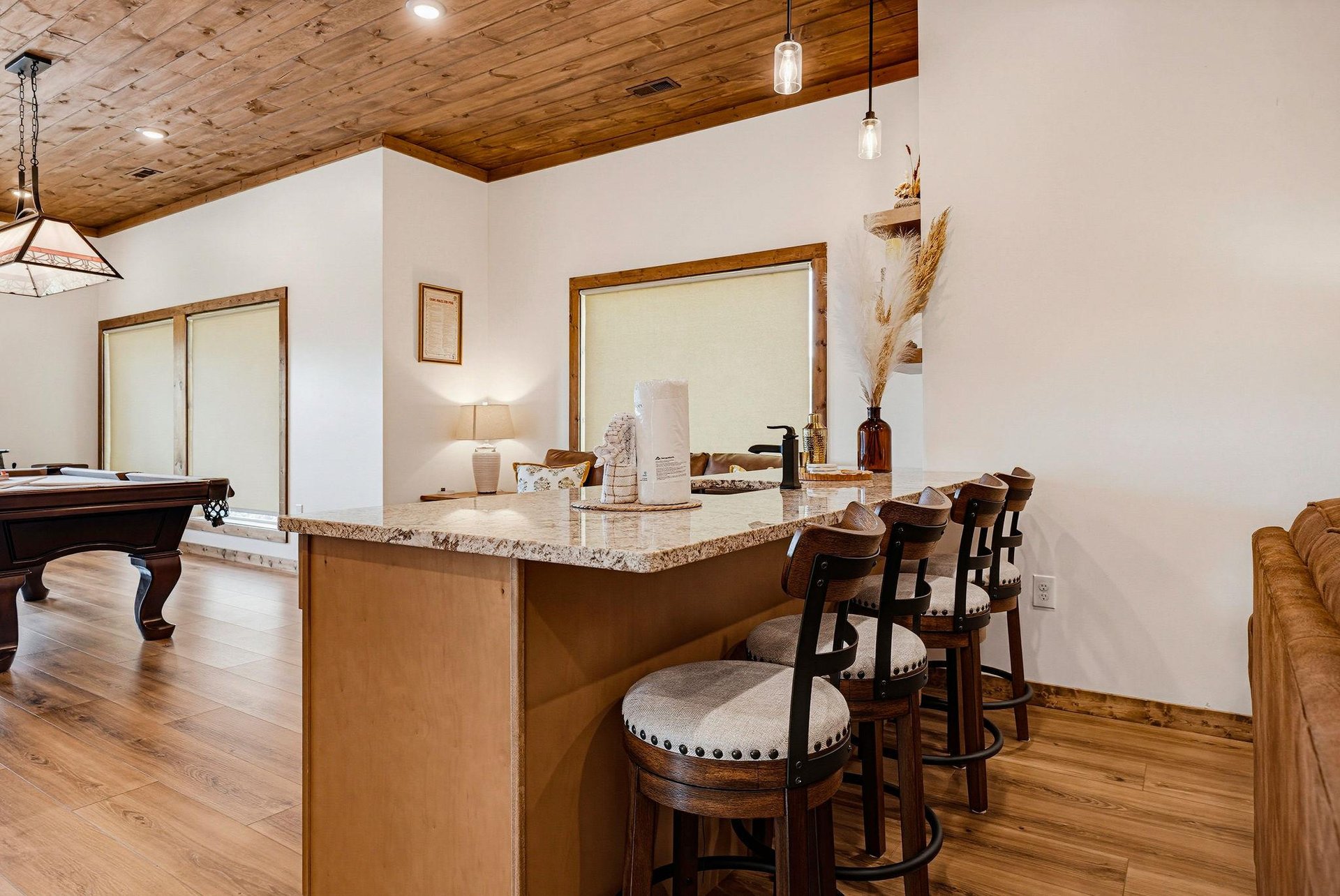 Pull up a seat at your stylish breakfast bar with marble countertop, perfect for morning coffee or casual meals. The woodplanked ceiling and hardwood floors add rustic charm, while nearby billiards o