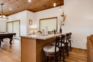 Pull up a seat at your stylish breakfast bar with marble countertop, perfect for morning coffee or casual meals. The woodplanked ceiling and hardwood floors add rustic charm, while nearby billiards o
