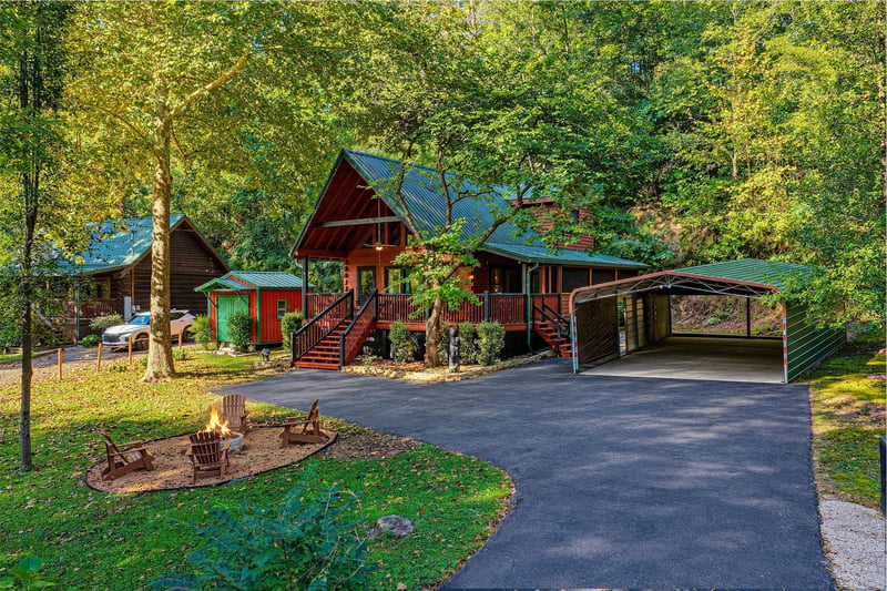 A charming cabin nestled among lush trees with covered parking and a welcoming fire pit for evening relaxation—your woodland retreat awaits.