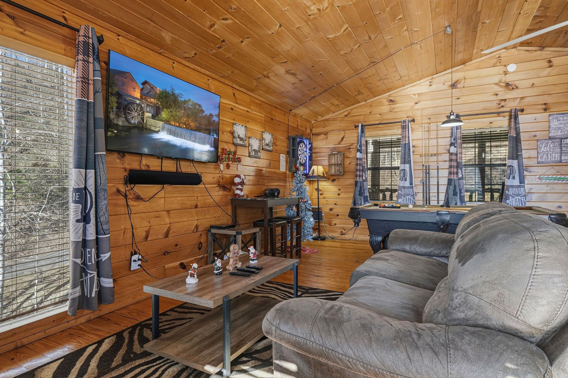 Cozy up in your rustic living room with warm wood walls, plush seating, and entertainment for memorable mountain evenings.