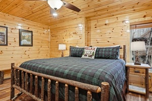 Drift off to sleep in your cozy log cabin bedroom, where rustic charm meets comfort with plaid bedding and warm wood surroundings.
