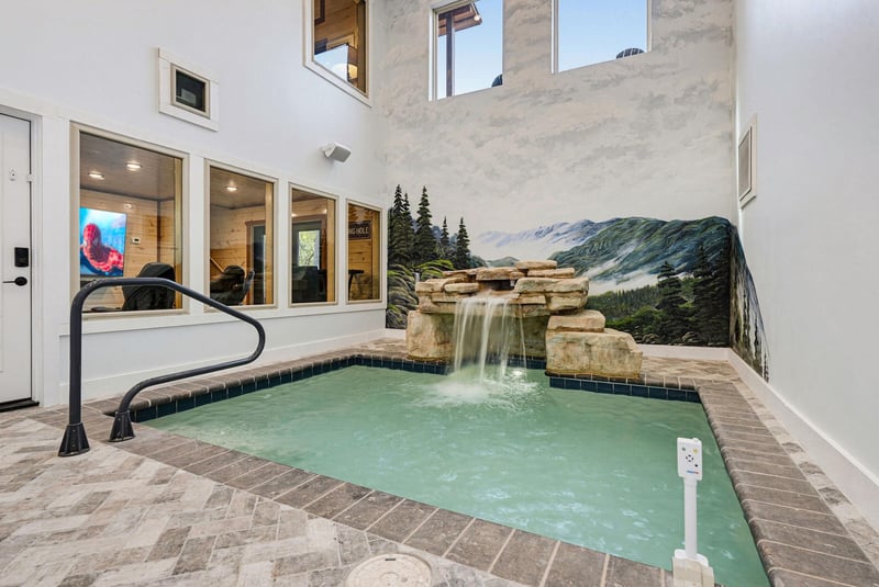 An indoor hot tub with cascading waterfall awaits your relaxation beneath soaring ceilings and natural light.